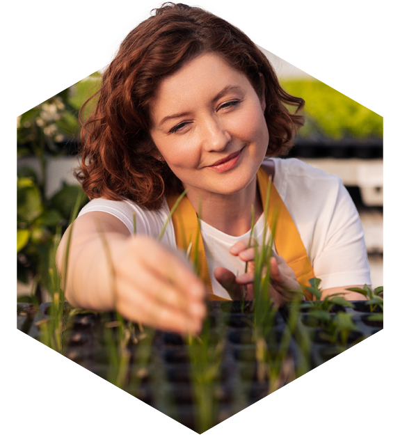 A woman tending to different plants in a greenhouse